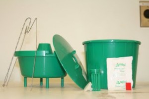 Grape root borer trap components. From left to right: hanger, trap top, trap lid, pheromone container (front), pheromone impregnated septa (packet, front), pesticide kill strip (red, front), and trap bottom (back). Photo: Hannah Burrack