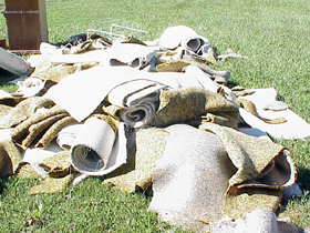 Water-logged carpet piled in front of a house.