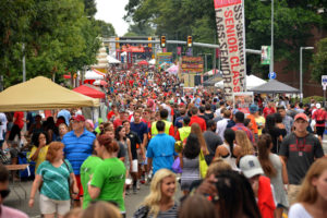 A crowd of people line the street during a public event at NC State University