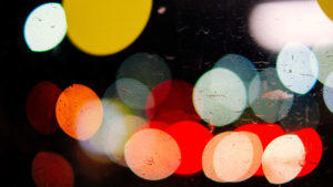 Street lights and car lights at night are distorted to look like big glowing balls of color in red, white and yellow