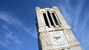 Top of the NC State University belltower with a bright blue sky in the background