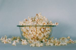 Popcorn in a glass bowl spilling out onto a counter