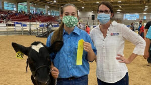 A female 4-H'er stands with her dairy steer and North Carolina Cooperative Extension 4-H Agent Holly Jordan during the 2020 WNC Livestock Expo.