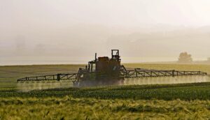 tractor spraying pesticide on field of crops