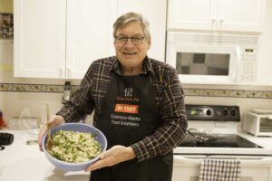 Extension Master Food Volunteer in kitchen wearing apron holding meal he has helped prepare