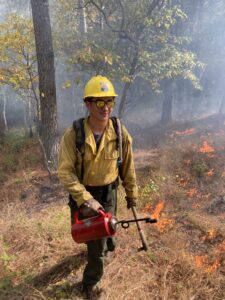 Image of Elliot Nauert holding a driptorch while managing a prescribed fire.