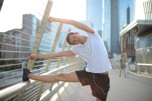 Person stretching with foot holding on to rail before physical activity