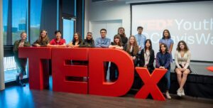 Youth gather around TEDx letters.