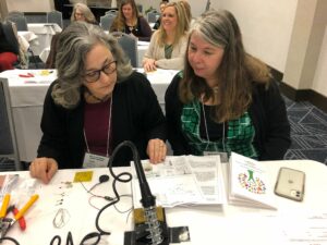 Two 4-H volunteers consult an instruction guide for an electricity activity.