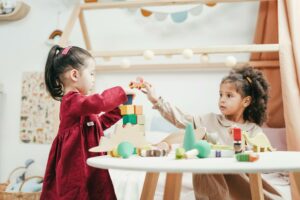 two children stacking blocks at a table
