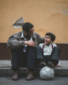 father and son sitting on sidewalk