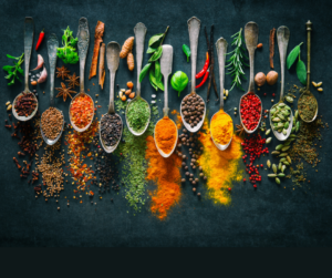 spoons line up on black background full of various herbs and spices