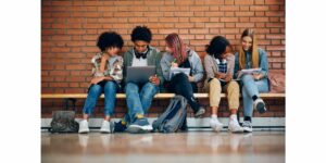 Kids on a bench with books and computers