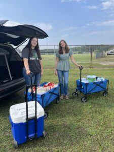 two peopling smiling and posing by wagons full of taste test materials