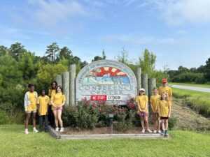 Pamlico County 4-H members standing in front of the sleepaway camp sign