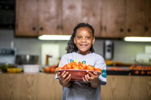 Child carrying platter of tomatoes