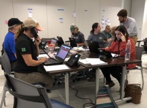 Group of people working at laptops and phones in an office after Hurricane Helene.