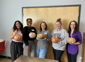 staff holding decorated pumpkins
