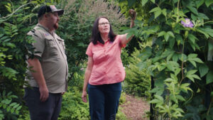 Holly Jordan, director of Extension's Buncombe County center, recognized for her leadership during Hurricane Helene recovery, gestures toward foliage in a garden as a colleague looks on.